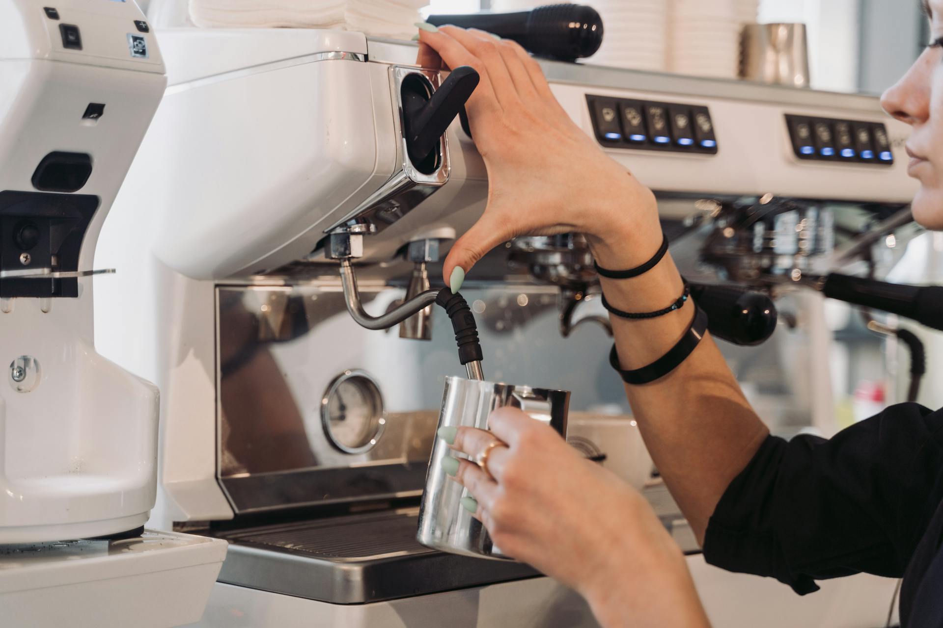 Eine Barista schäumt Milch an einer Siebträgermaschine auf.