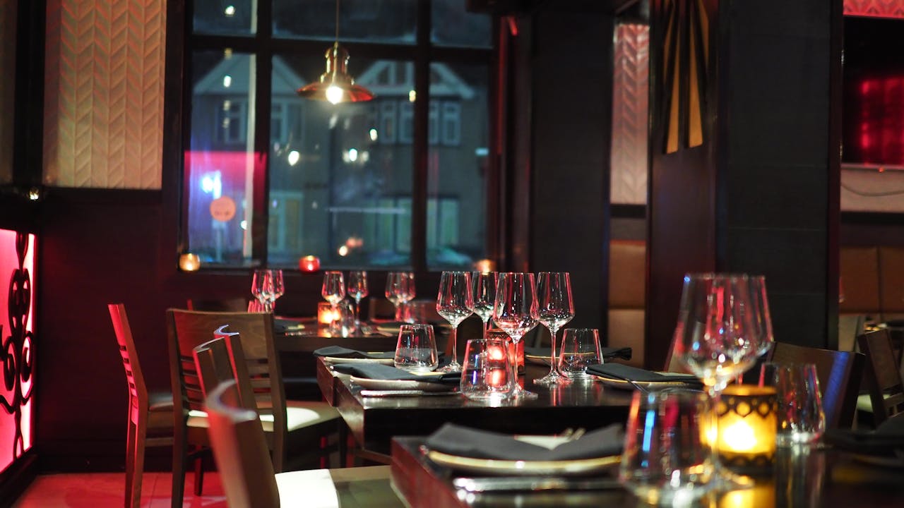 Innenansicht eines Restaurants am Abend. Die Tische sind edel gedeckt und Kerzen sind auf den Tischen.