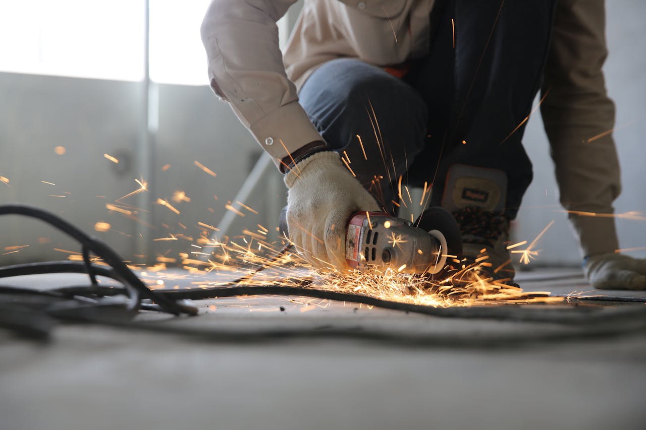 Baustelle auf der ein Handwerker mit einem Winkelschleifer arbeitet.