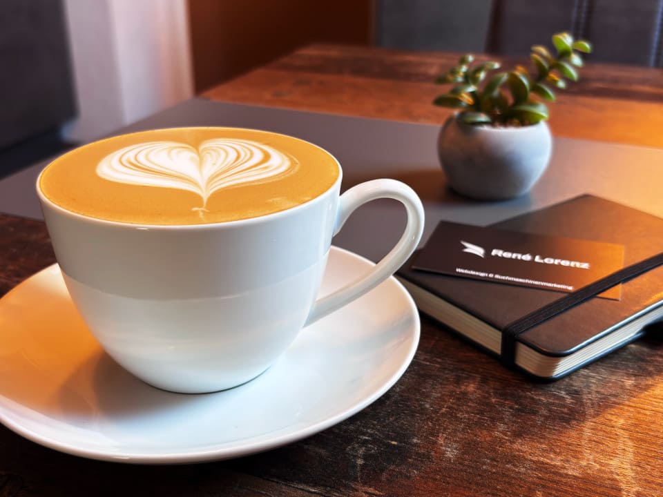 Café Latte und daneben ein Notizbuch auf dem eine Visitenkarte liegt der Agentur "René Lorenz | Local SEO / SEA & Webdesign".